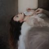 Ritratto di una donna distesa sul letto, sognante, tra le lenzuola bianche. Diletta Innocenti Fagni
